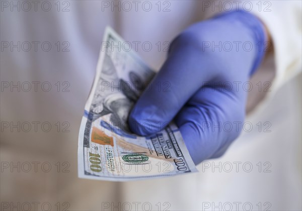 Person in surgical glove holding money