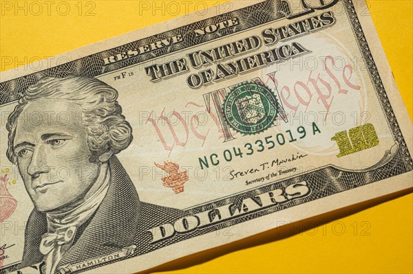 Close-up of US ten dollar bill on yellow