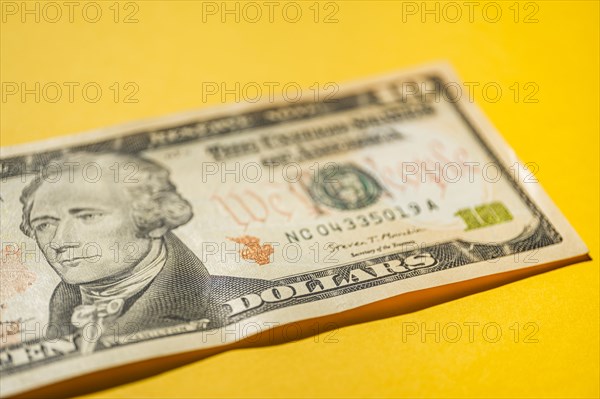 Close-up of US ten dollar bill on yellow