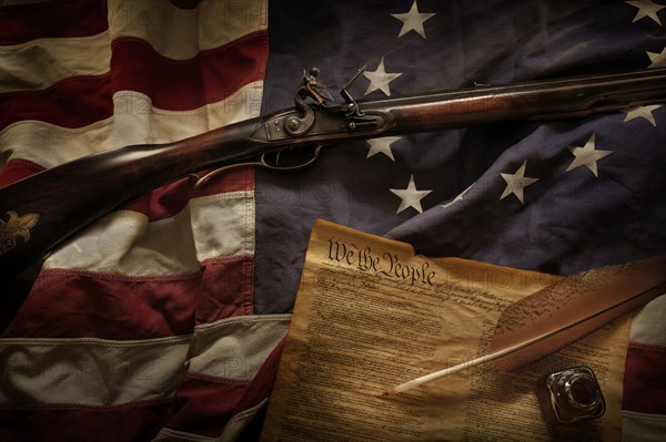 Rifle and US constitution lying on American flag