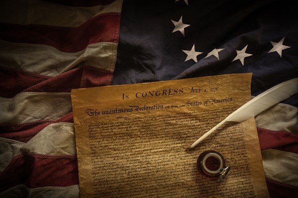 Declaration of independence, quill and ink lying on American flag,