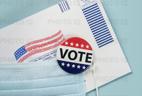 Envelope, election pin and face mask against blue,