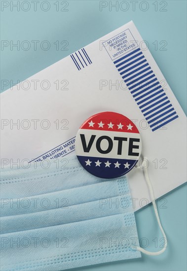 Envelope, election pin and face mask against blue,