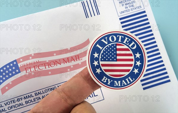 Human finger holding sticker above voting mail,,
