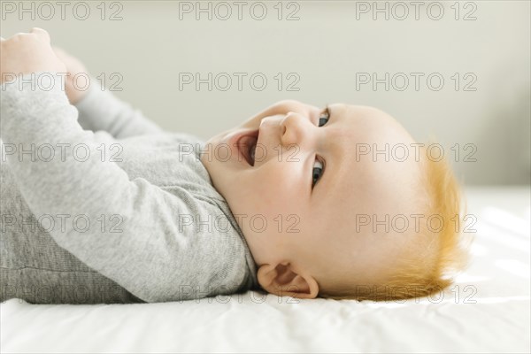 Smiling baby boy lying on bed