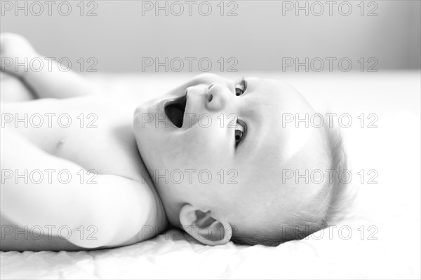 Smiling baby boy lying on bed