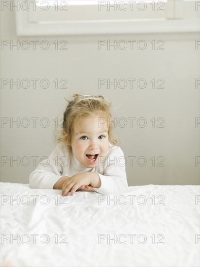 Portrait of toddler girl leaning on bed