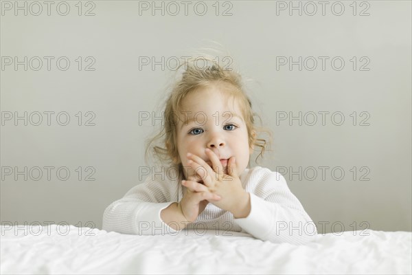 Portrait of toddler girl leaning on bed