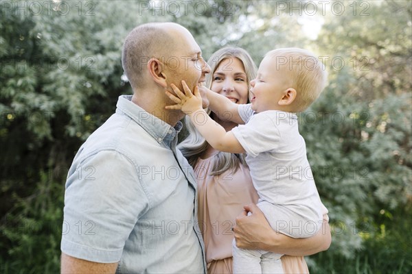 Happy parents standing in garden with baby son