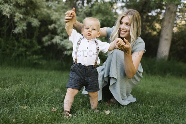 Mother with baby son learning to walk in park