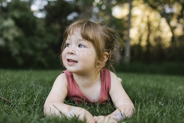 Girl (2-3) lying on grass