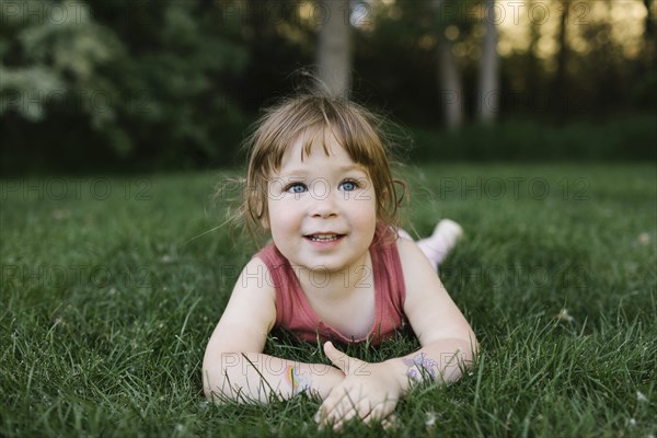 Girl (2-3) lying on grass