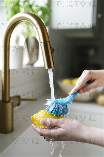 Woman washing lemon with brush