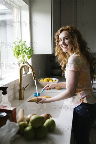 Woman washing sweet potato with brush