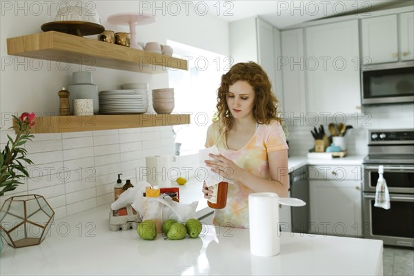 Woman cleaning jar in kitchen