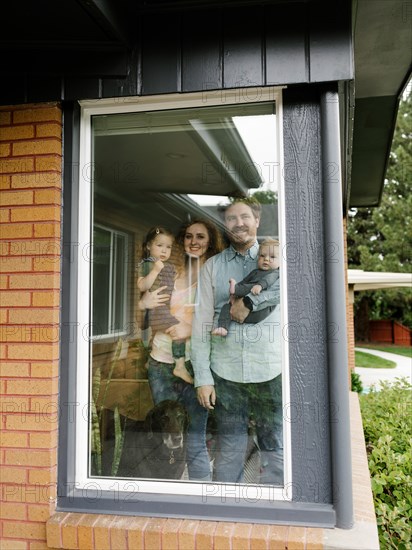 Family with children (6-11 months, 2-3) looking through window,