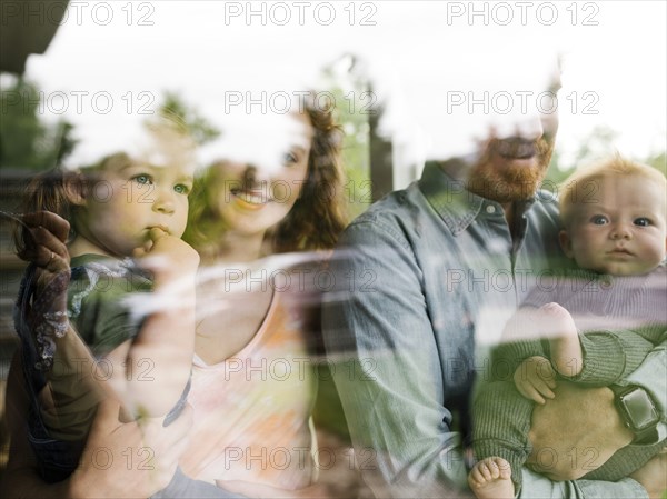 Family with children (6-11 months, 2-3) looking through window,