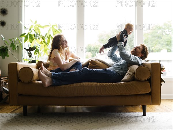 Mother and father playing with baby son (6-11 months) on sofa