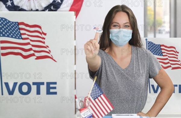 Woman in face mask holding voting sticker