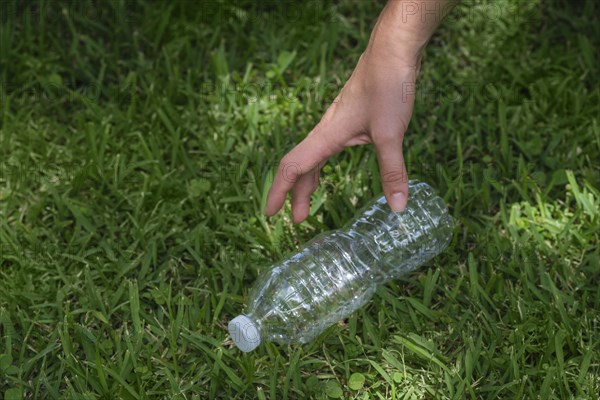 Woman's hand picking up plastic bottle