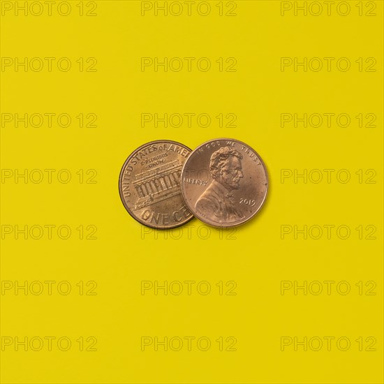 Front and back of two pennies on yellow background