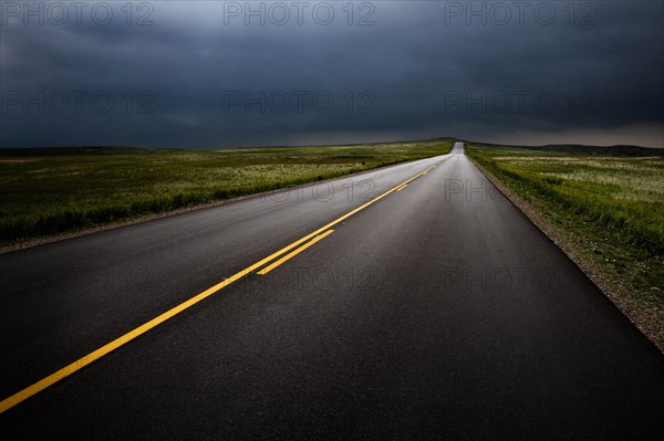 USA, South Dakota, Badlands National Park, Storm clouds over road in prairie