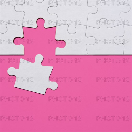 Last puzzle piece in jigsaw puzzle on pink background