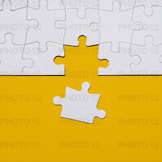 Last puzzle piece in jigsaw puzzle on yellow background