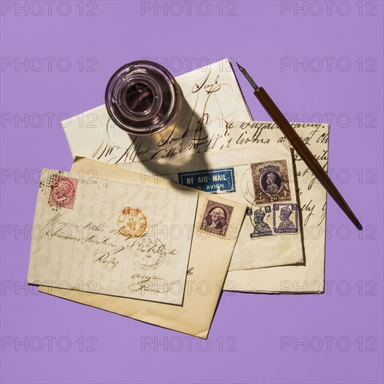 Antique ink well and old letters on purple background