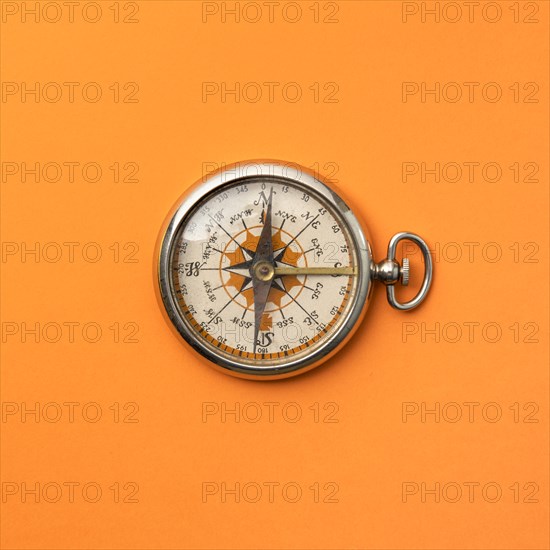 Antique compass on orange background