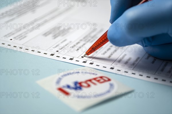 Badge and hand filling voting form on blue background