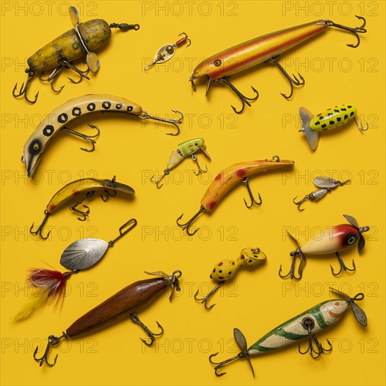 Arranged group of vintage fishing lures on yellow background