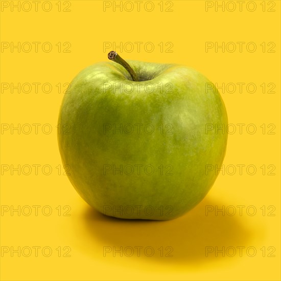 Green apple against yellow background