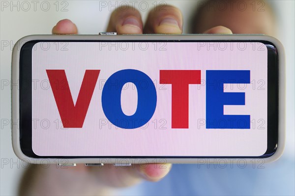 Hand holding smartphone with voting message