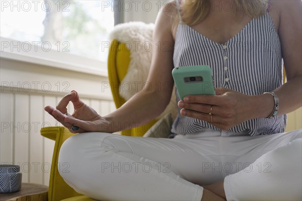 Midsection of woman using smartphone and practicing yoga