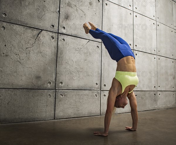 Woman doing handstand against wall