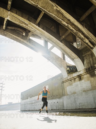 USA, California, Los Angeles, Sporty woman running underneath bridge