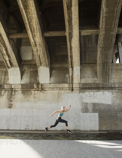 USA, California, Los Angeles, Sporty woman running underneath bridge