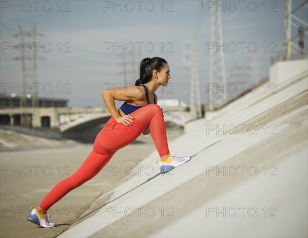 USA, California, Los Angeles, Sporty woman stretching in urban setting