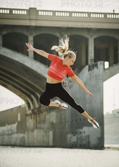 USA, California, Los Angeles, Sporty woman jumping in urban setting