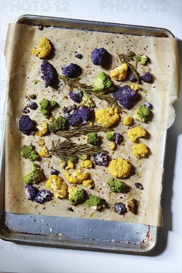 Roasted cauliflower with rosemary and olive oil on parchment paper