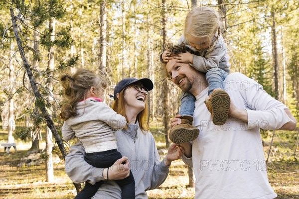 Happy parents carrying little daughters