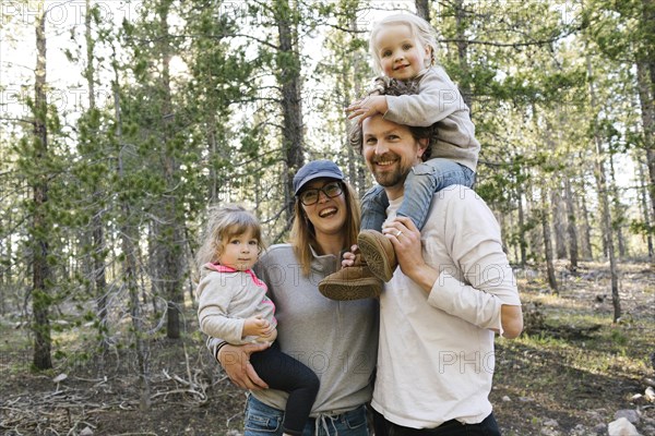 Portrait of happy parents carrying little daughters