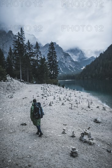 Italy, Pragser Wildsee, Dolomites, South Tyrol, Man at lake shore among stone stacks