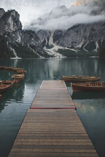 Italy, Pragser Wildsee, Dolomites, South Tyrol, Rowboats moored near jetty in mountain lake