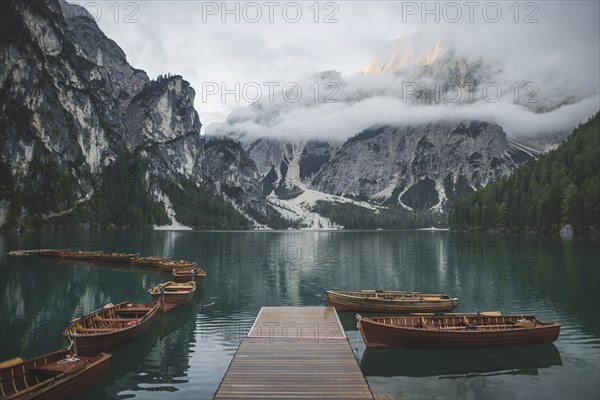 Italy, Pragser Wildsee, Dolomites, South Tyrol, Rowboats moored near jetty in mountain lake