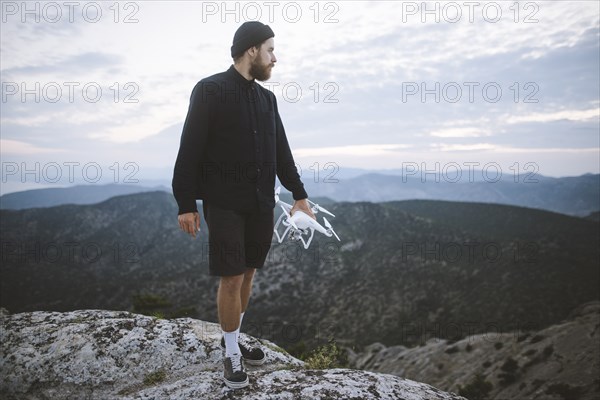 Italy, Liguria, La Spezia, Man at mountain top holding drone