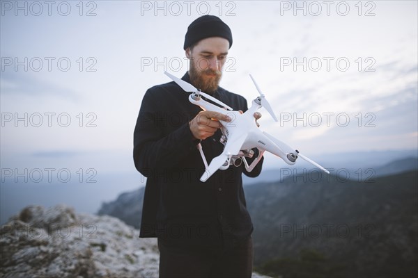 Italy, Liguria, La Spezia, Man at mountain top holding drone