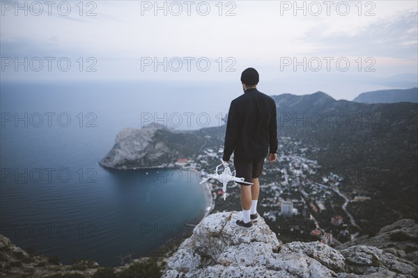 Italy, Liguria, La Spezia, Man at mountain top holding drone