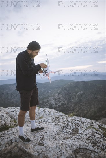 Italy, Liguria, La Spezia, Man at mountain top holding drone